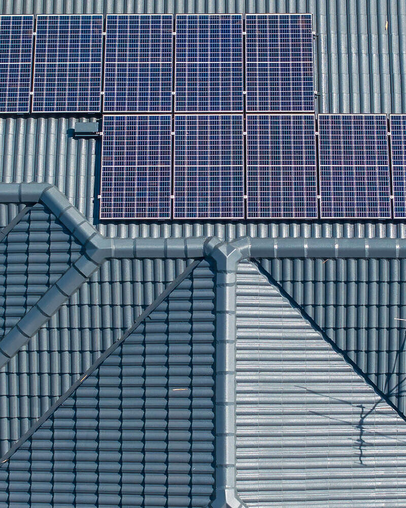 Close-up drone roof inspection photo of tiles, ridge capping and solar panels in Kedron